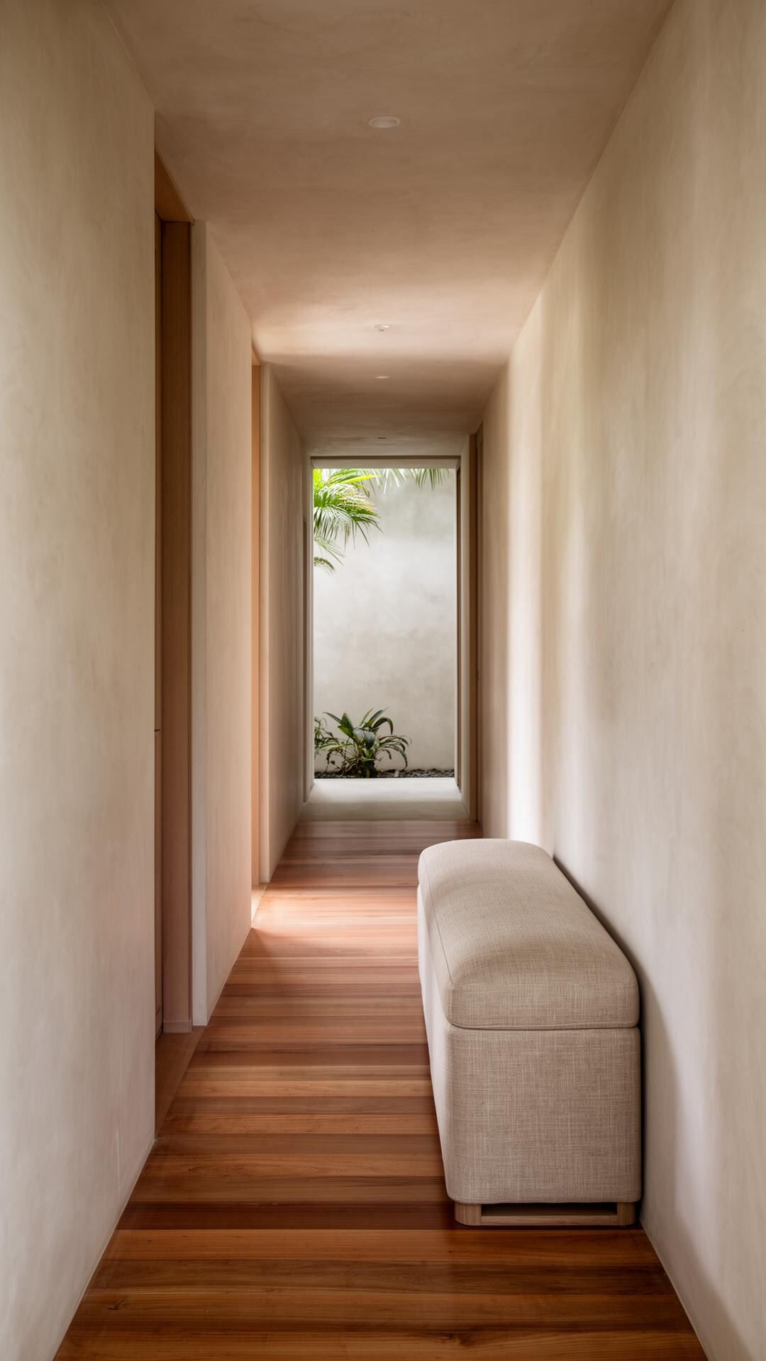 A still hallway in a tropical residence with a single linen bench